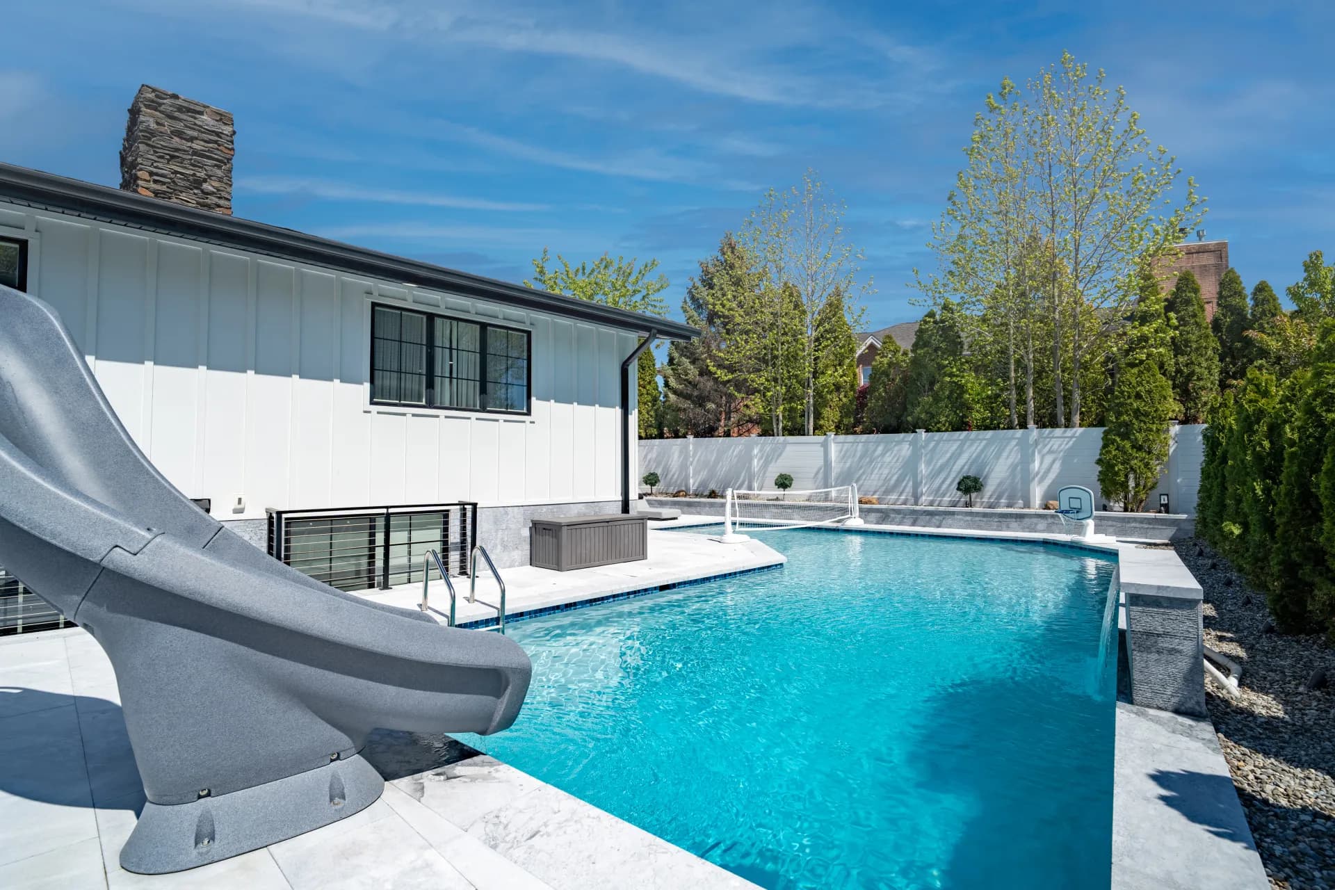 Backyard pool after renovation — resurfaced pool with slide, new patio and landscaping