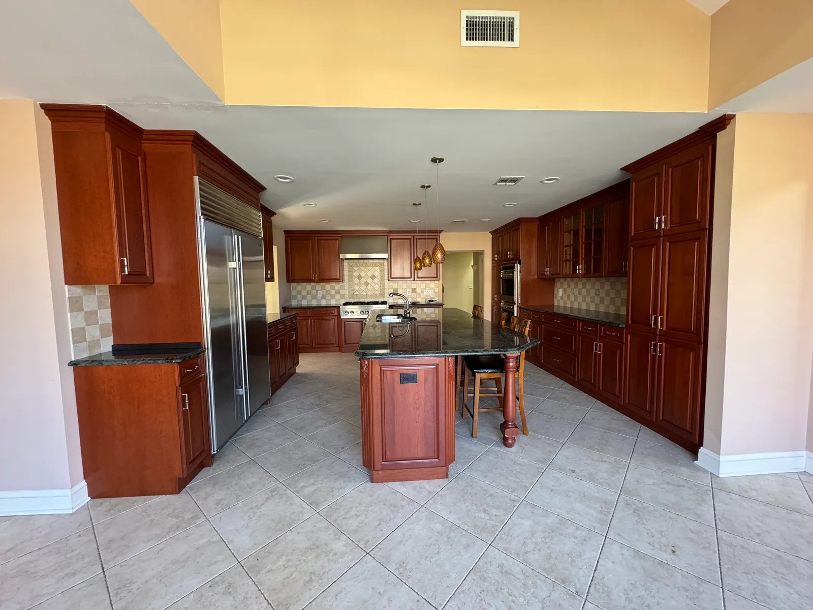 Kitchen before renovation — dated cherry cabinetry and tile floor