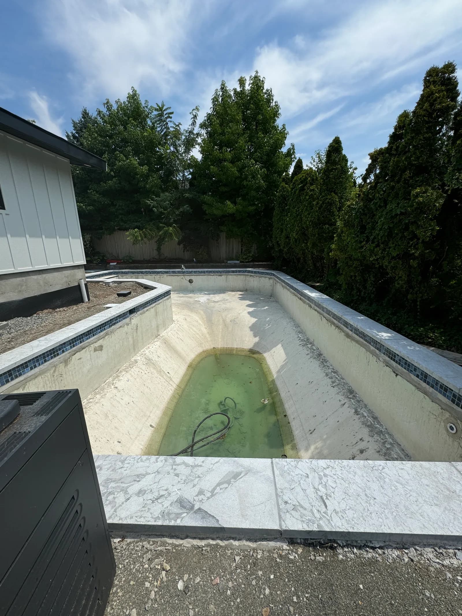 Backyard pool before renovation — empty and stripped for rebuild