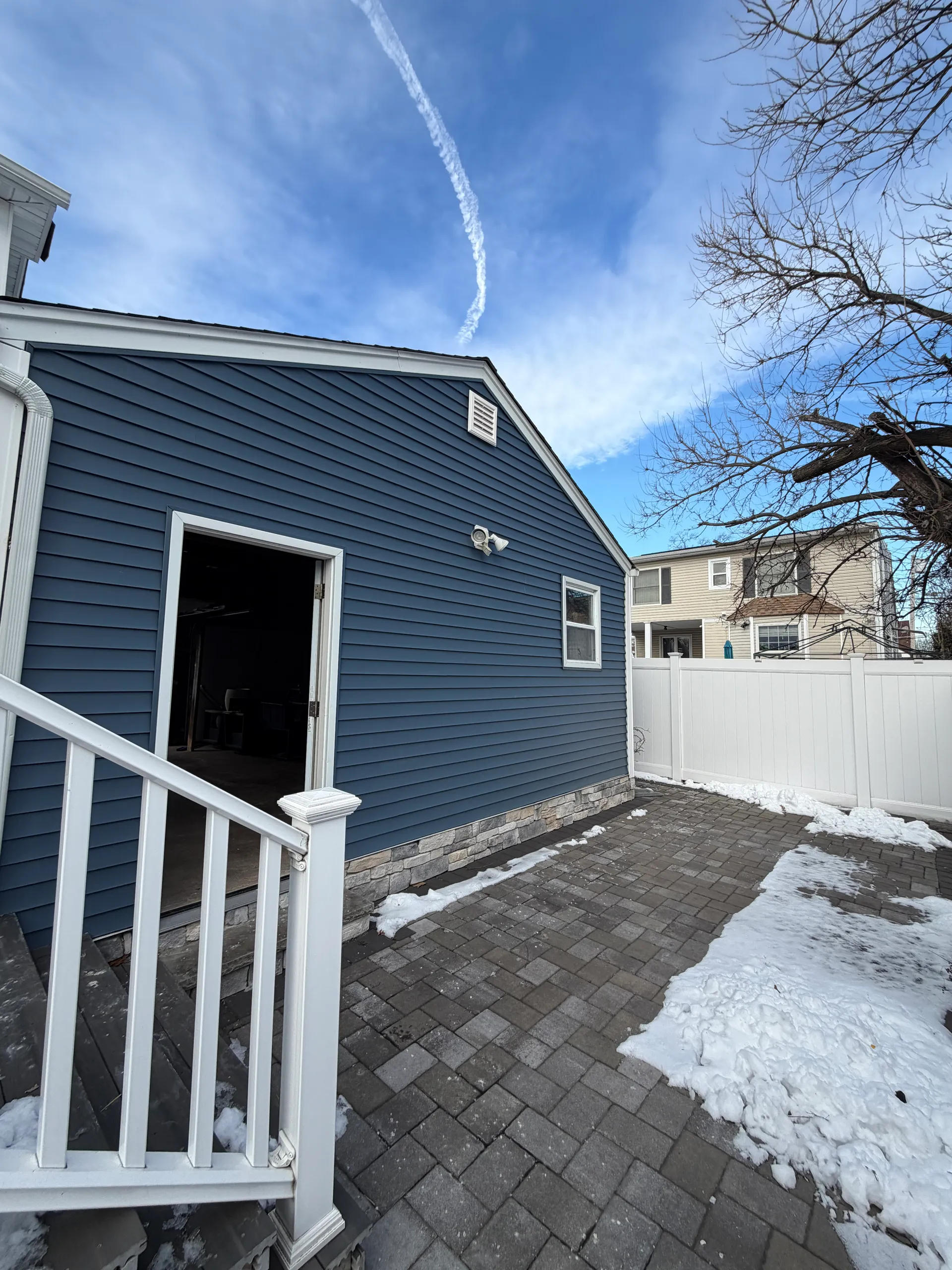 Rear exterior with new siding and paver patio during renovation