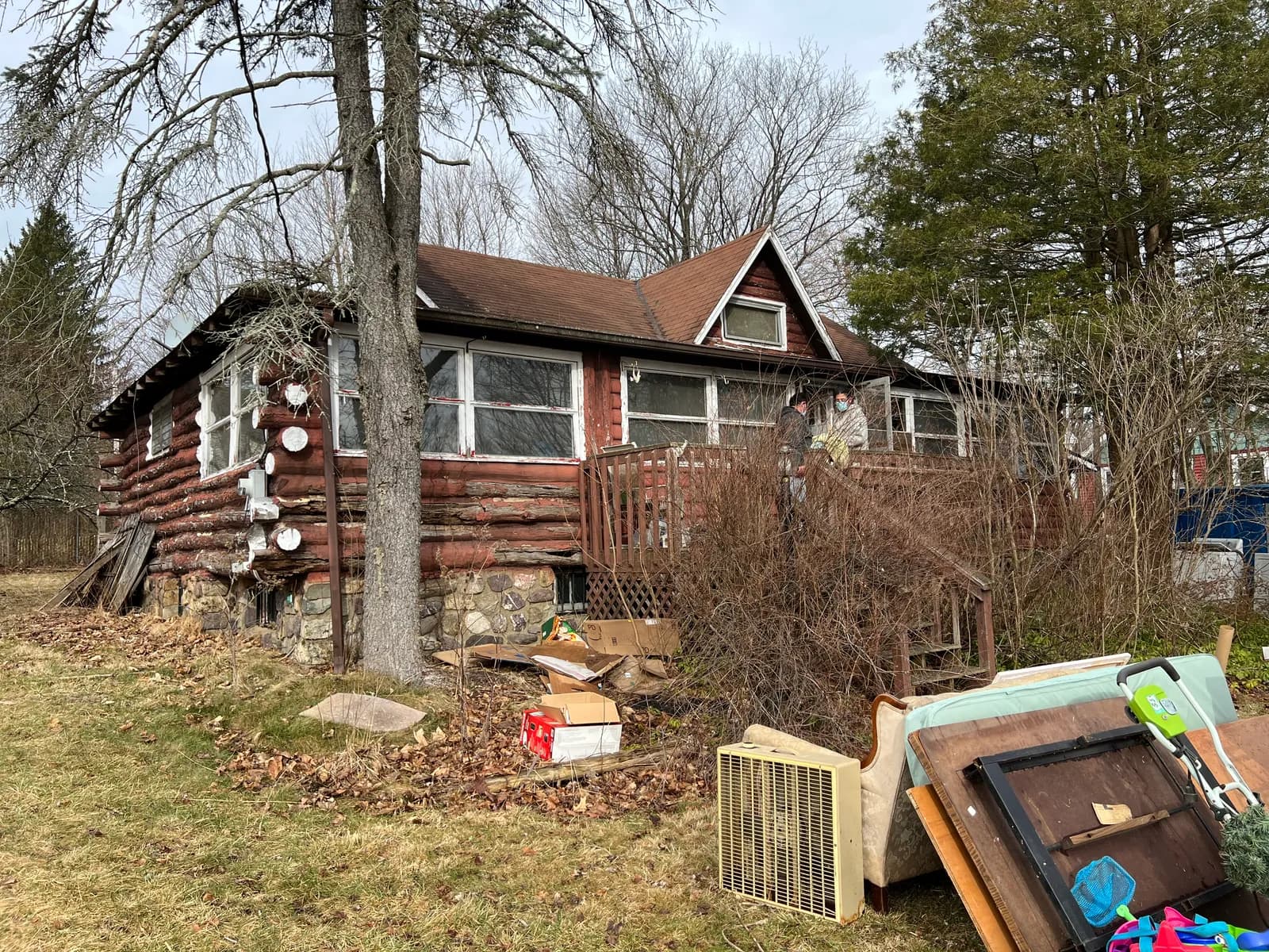 Neglected log cabin before renovation — weathered logs and debris