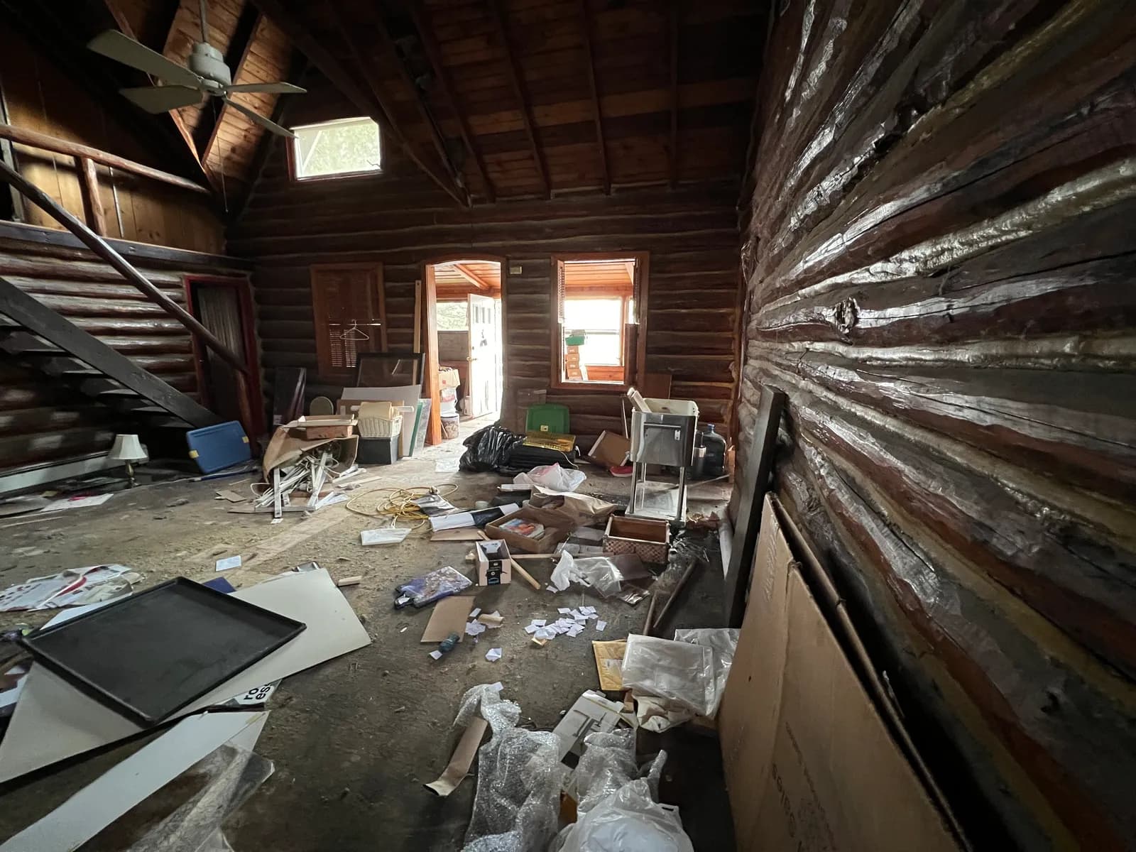 Gutted cabin interior with debris around the stone fireplace