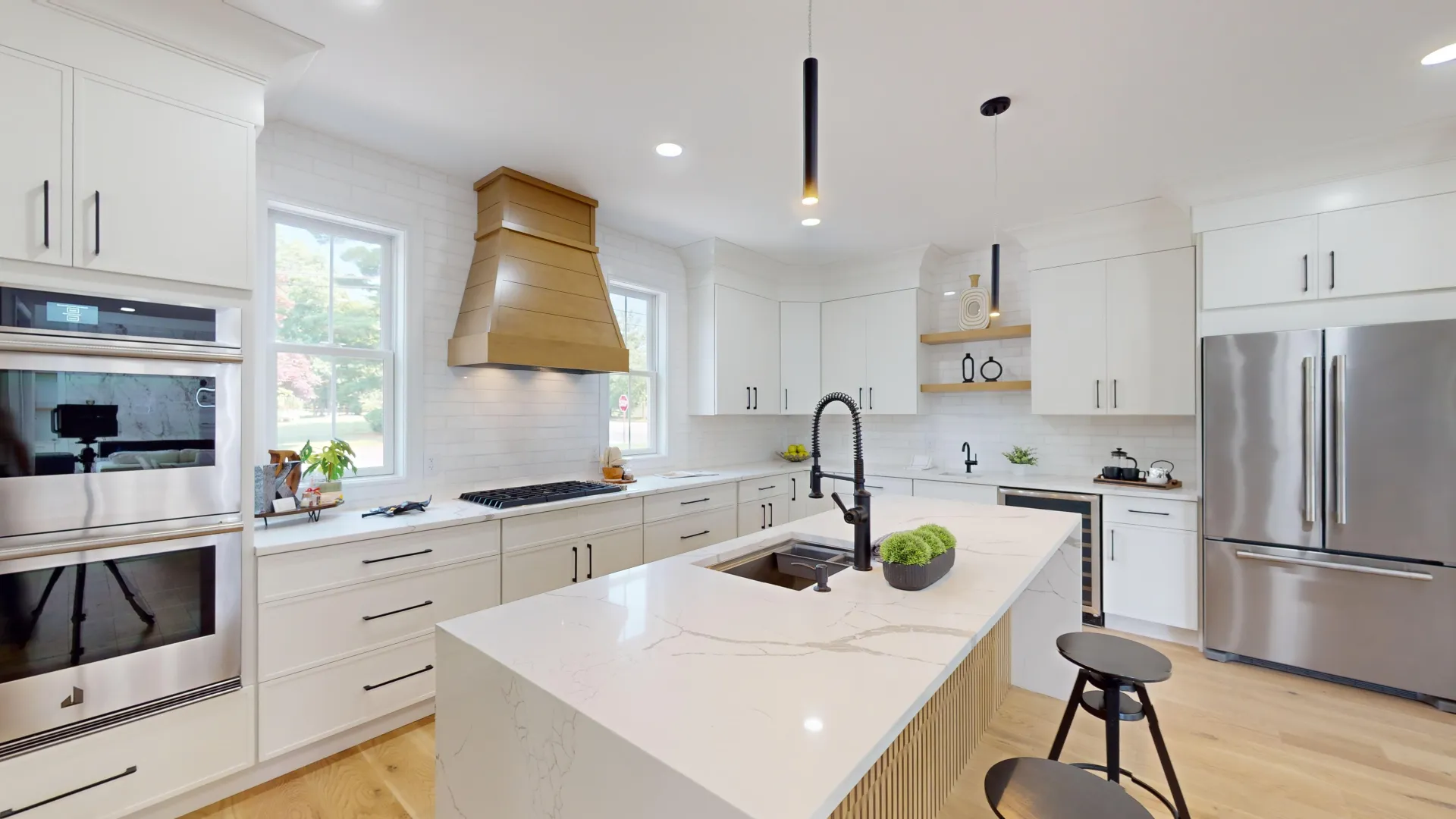 Finished kitchen — custom white cabinetry, brass hood, and quartz island