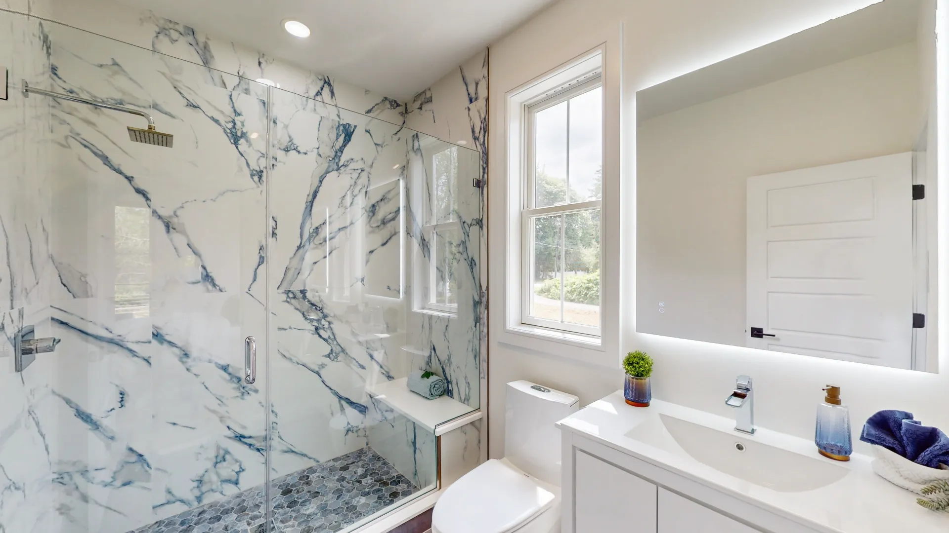 Finished primary bath — book-matched marble shower and floating vanity