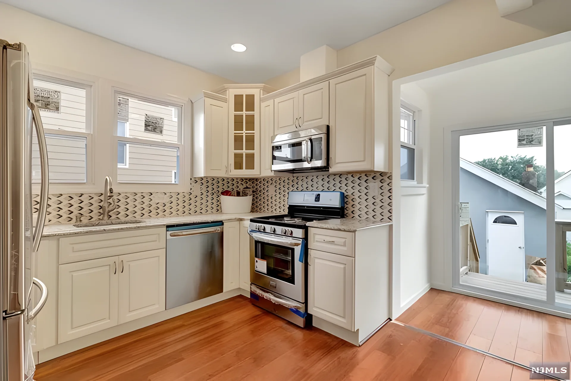 Finished kitchen — new cabinetry, tile backsplash, and stainless appliances