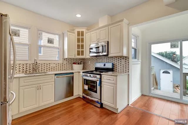 Finished kitchen — new cabinetry, tile backsplash, and stainless appliances