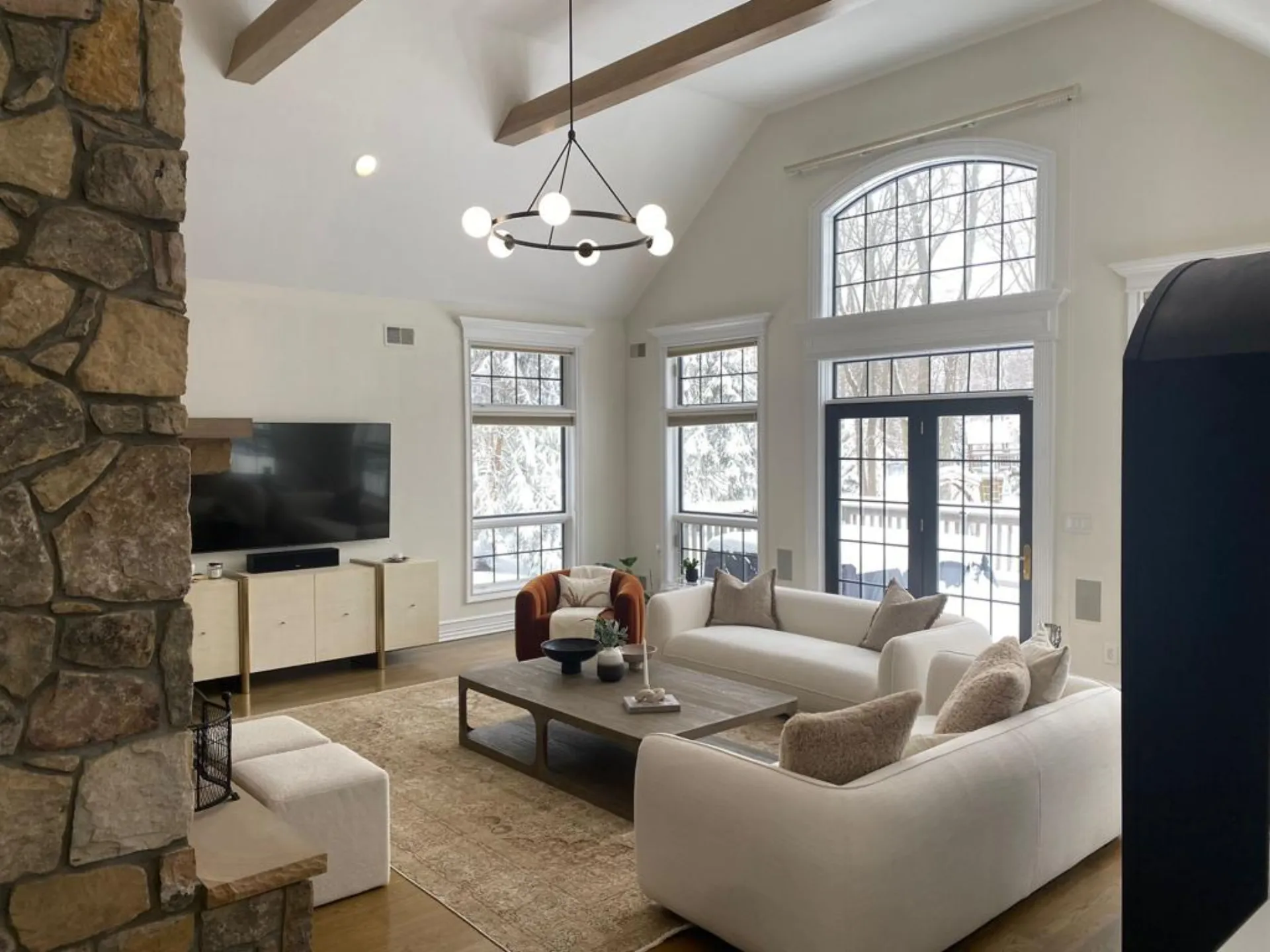 Finished great room — vaulted ceiling, exposed beams, and floor-to-ceiling stone fireplace