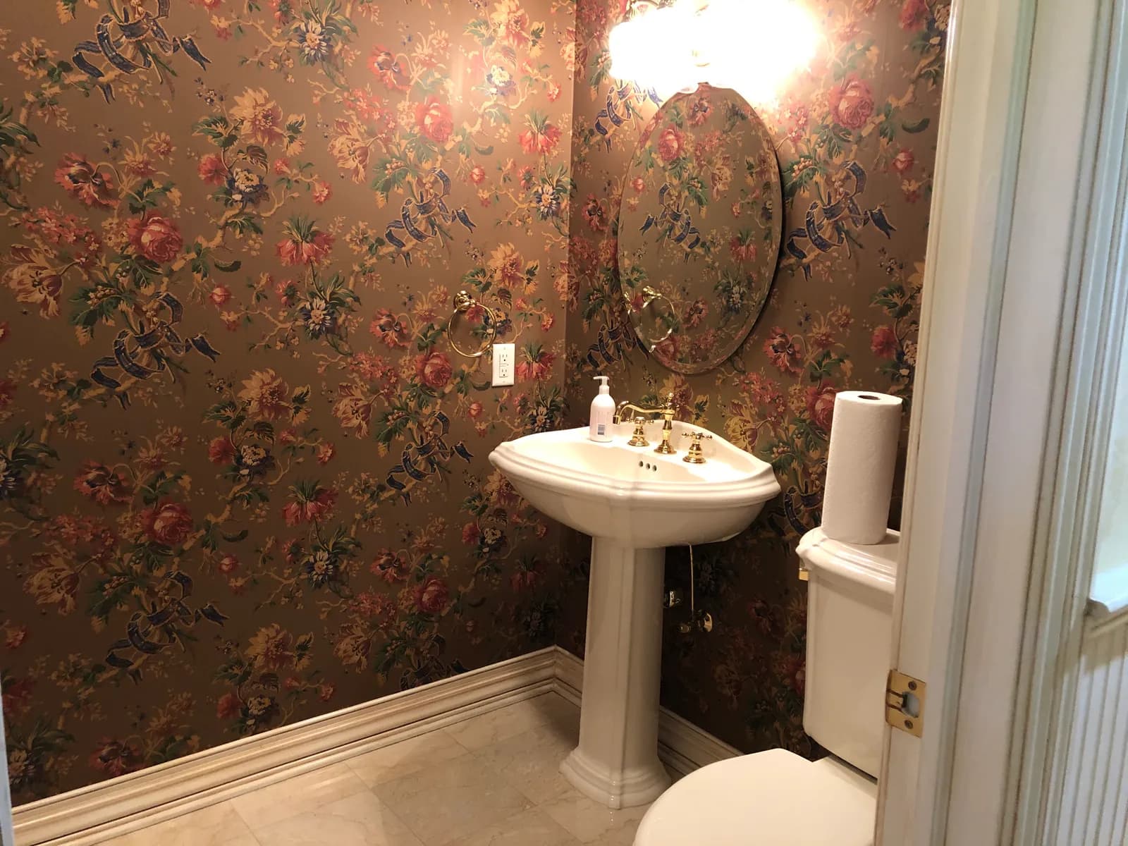 Bathroom before renovation — floral wallpaper and pedestal sink